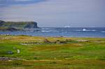 Stock photo of view from the Information Centre at L'Anse aux Meadows National Historic Site of Canada and UNESCO World Heritage Site, over the sod huts of the site towards icebergs in Iceberg Alley and the Atlantic Ocean coastline, Northern Peninsula, Gr