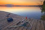 Stock photo of fishing equipment laying on the wooden wharf with the sun setting in the background at Lake Audy, Riding Mountain National Park, Manitoba, Canada.