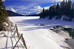 Stock photo of a partially frozen Maligne River and a wooden fence under a blue sky during winter as the river drains from Maligne Lake, with a view towards Samson Peak from along Maligne Lake Road, Jasper National Park, Canadian Rocky Mountains, Alberta,