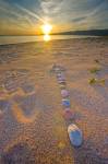Stock photo of a rock design in the shape of an arrow pointing toward the setting Sun on the beach at Agawa Bay in Lake Superior Provincial Park, Ontario, Canada.