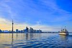 Stock photo of Toronto's skyline against a clear, cloudy, and blue sky with CN Tower and Toronto Islands Ferry in the City of Toronto, Ontario, Canada.