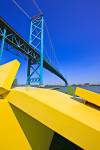 <p>Stock photo of a bright yellow sculpture in Odette Park, Windsor, Ontario and the Ambassador bridge in the background.</p>