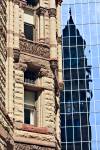 Stock photo showing the stone facade of the Old City Hall building beside a modern mirrored skyscraper reflecting a dark shadow of the multicolored stone architecture in downtown Toronto, Ontario, Canada.