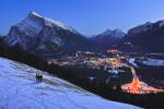 Stock photo of an aerial view at dusk of the town of Banff viewed from Norquay Meadow along Mount Norquay Road during winter after snow fall with Mount Rundle to the left, Banff National Park, Canadian Rocky Mountains, Alberta, Canada. Banff National Park