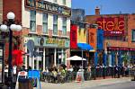 Stock photo of a colorful cafe/restaurant street scene at the Byward Market in the City of Ottawa, Ontario, Canada. People are seen dining at outside tables surrounded by shops on this busy street.