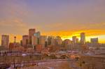Stock photo of the Calgary skyline at sunset with high-rise buildings, the Calgary Tower, and the Centre Street Bridge spanning the Bow River at sunset after light snowfall during early winter in the City of Calgary, Alberta, Canada.