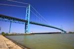 Stock photo of large bulk carrier ship passing under Ambassador Bridge expanding the Detroit River from Windsor, Ontario Canada to Detroit, Michigan, United States