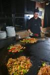 Stock photo of a chef performing with utensils and food while preparing meals at the Mongolie Grill World Famous Stirfry Restaurant in Whistler Village, British Columbia, Canada. 