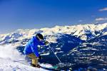 Stock photo of a downhill skier on the upper slopes of Whistler Mountain, Whistler Blackcomb, Whistler, British Columbia, Canada. Snow-capped mountains and blue sky provide the background for this sunny Winter scene in which you can only see a small piece