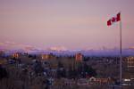 Stock photo of Canadian flag flying high over the city of Calgary with the Canadian Rocky Mountains in background.