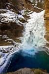 Stock photo of the partially frozen Lower Falls of the Johnston Creek during winter surrounded by ice and snow formations, Johnston Canyon, Banff National Park, Canadian Rocky Mountains, Alberta, Canada.