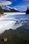 Srock photo of a partially frozen Maligne River in Winter as it drains from Maligne Lake, with a view of Leah and Samson Peaks along Maligne Lake Road in Jasper National Park in the Canadian Rocky Mountains in Alberta, Canada.