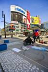 Stock photo of an artist drawing with chalk on the pavement with buildings and blue sky in the background in downtown Toronto, Ontario, Canada. 