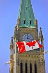 Stock photo of the Canadian flag in front of the Peace Tower of the Parliament Building and blue sky in Ottawa in Ontario, Canada.