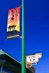 Stock photo of a colourful red, orange, and black banner hanging above the street sign on this tall green pole in Chinatown, City of Winnipeg, Manitoba, Canada.