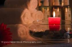 Red candle glowing with towels in background.