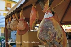 Hams hanging to dry at market stall during Medieval Festival in Plaza de la Corredera
