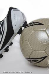 Soccer shoe leaning against a soccer ball