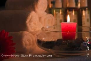 Stock photo of a closeup of a round glass bowl with a vivid red candle sitting on a tabletop.
