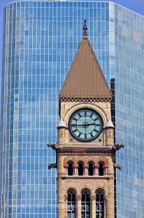 Stock photo of the Clock tower at the old City Hall building in downtown Toronto, Ontario Canada. the top portion of the clock tower is seen with its row of three tall arched windows above a row of four smaller windows in the sand colored stone of the edi