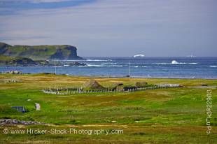 Stock photo of view from the Information Centre at L'Anse aux Meadows National Historic Site of Canada and UNESCO World Heritage Site, over the sod huts of the site towards icebergs in Iceberg Alley and the Atlantic Ocean coastline, Northern Peninsula, Gr