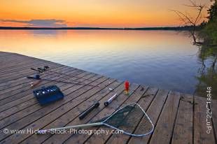 Stock photo of fishing equipment laying on the wooden wharf with the sun setting in the background at Lake Audy, Riding Mountain National Park, Manitoba, Canada.