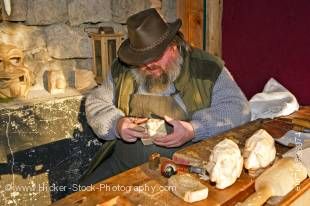 Stock photo of a bearded man carving the heads of puppets at the Christmas Markets at the Hexenagger Castle, Hexenagger, Bavaria, Germany, Europe.