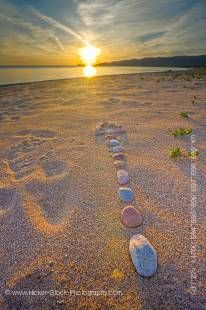 Stock photo of a rock design in the shape of an arrow pointing toward the setting Sun on the beach at Agawa Bay in Lake Superior Provincial Park, Ontario, Canada.